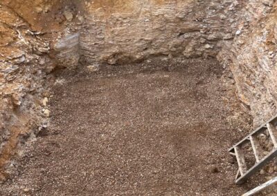Excavated pit filled with gravel and a metal ladder leaning on the edge. - Fosker Plumbing Western Sydney