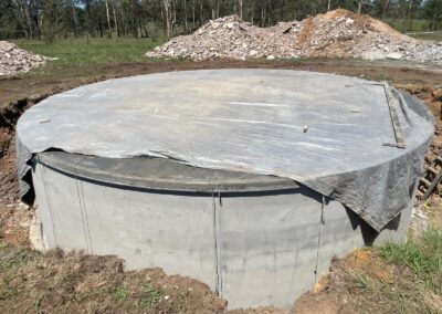 Large cylindrical concrete septic tank installation covered with protective tarp outdoors. - Fosker Plumbing Western Sydney